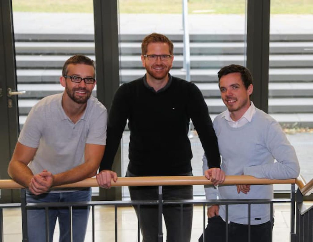 Die drei Gründer von FlexHero, Damian Belter, Frank Blasius und Philipp Klönhammer stehen auf einer Treppe