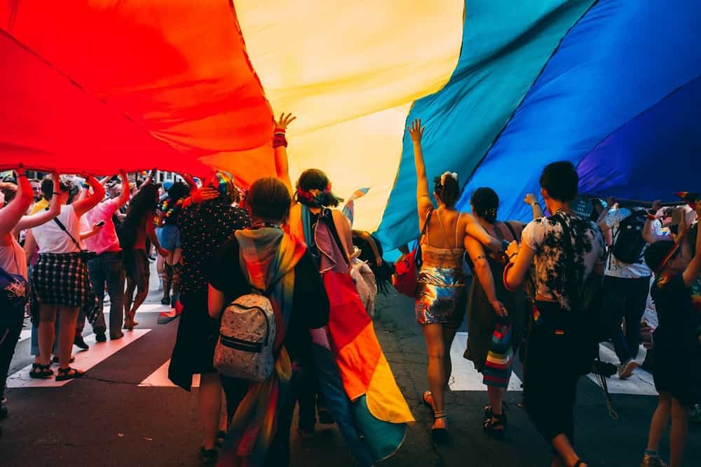 Ehrenamtliche Aktivisten stehen unter Regenbogenfahne