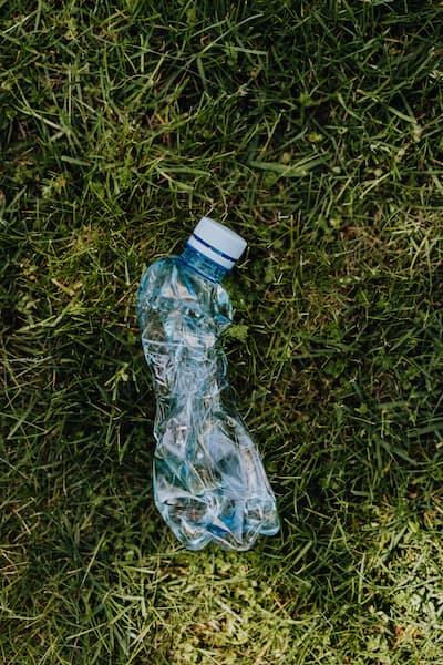 Plastikflasche die zerdrückt im Rasen liegt